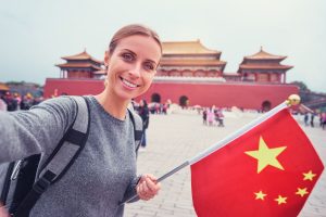 Young woman with national chinese flag taking selfie in Forbidden City.