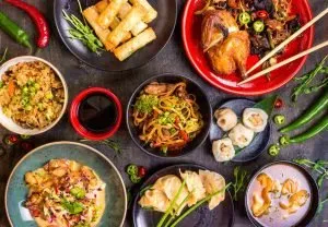 Assorted Chinese food set. Chinese noodles, fried rice, dumplings, peking duck, dim sum, spring rolls. Famous Chinese cuisine dishes on table. Top view. Chinese restaurant concept.