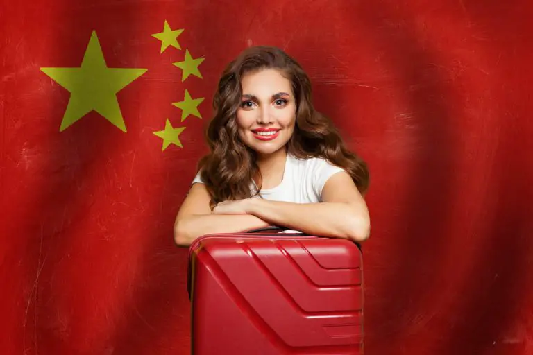 Beautiful woman with red suitcase on the People's Republic of China flag background.