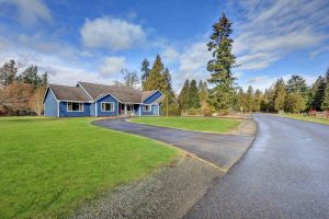 Beautiful rambler house with tile roof, blue siding and well kept lawn in the front yard. Northwest, USA