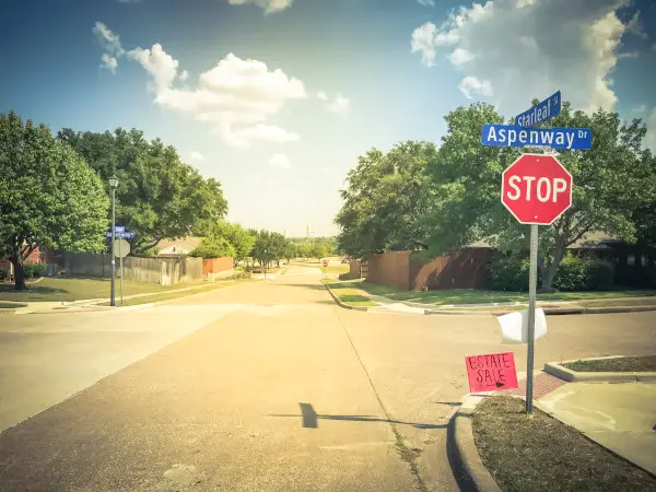 All way stop and estate sale sign at suburban neighborhood near Dallas, Texas, America. Lawn sale sign on the sidewalk near local drive intersection