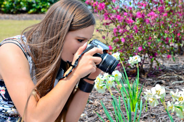 A teenager taking a photograph of her garden flowers.