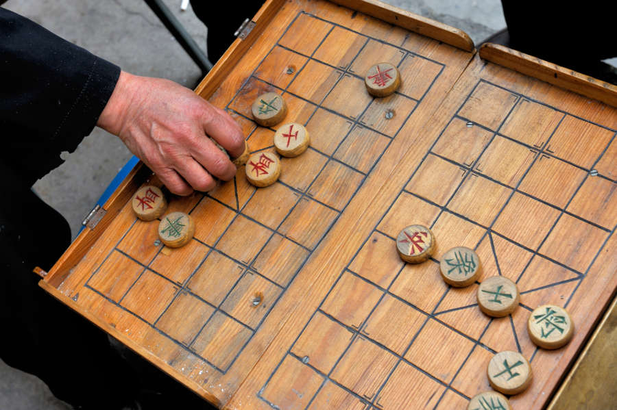 chinese board games -A man makes a move on a on a local Beijing Chinese chess game board. xiangqi, also known as Chinese chess, is an ancient board game played all over the world.